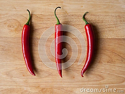 Three chilli peppers on wood Stock Photo