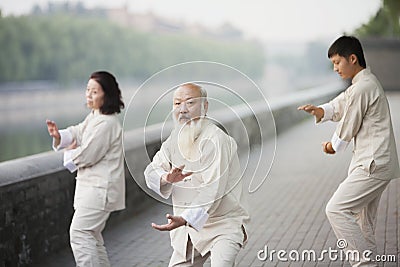 Three Chinese People Practicing Tai Ji Outdoors Stock Photo