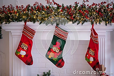 Three Christmas socks decorated with owl figures hanging on a shelf under advent garland Stock Photo