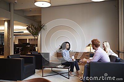 Three colleagues at a casual work meeting in a lounge area Stock Photo