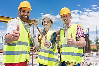 Three colleagues in a construction team showing thumbs up Stock Photo