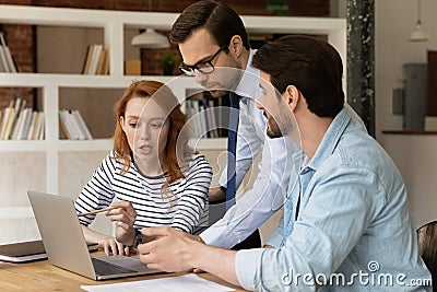 Three colleagues coworkers working on project together, using laptop Stock Photo