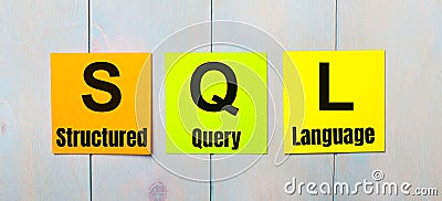 Three colored stickers with the text SQL Structured Query Language a light blue wooden background Stock Photo