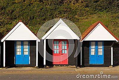 Three colourful beach huts with blue and red doors in a row Stock Photo