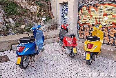 Three colourful retro scooters standing beside each other on the street in Barcelona, Spain Editorial Stock Photo