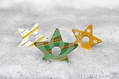 Three colourful wooden Christmas stars in the snow Stock Photo