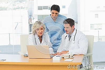 Three concentrated doctors using laptop together Stock Photo