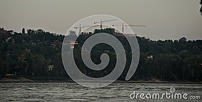 Three cranes on other side of river Danube Stock Photo