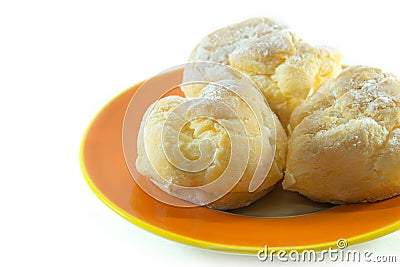 Three cream puffs on orange plate closeup Stock Photo