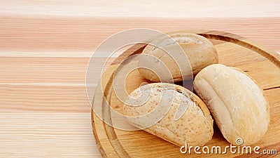 Three crusty petit pain on a bread board Stock Photo