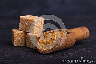 Three cubes of cane sugar and a wooden spoon with sugar sand Stock Photo