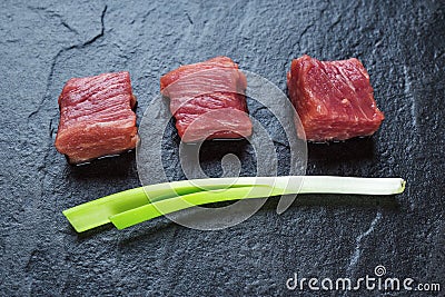 Three cubes of meat and green onions Stock Photo