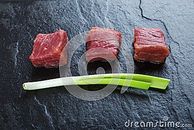 Three cubes of meat and green onions Stock Photo