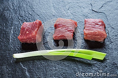 Three cubes of meat and green onions Stock Photo