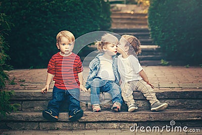 Three cute funny adorable white Caucasian children toddlers boys girl sitting together kissing each other Stock Photo