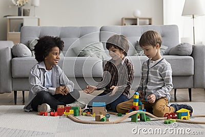 Three cute multiethnic boys play wooden railway at home Stock Photo