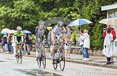 Three Cyclists Riding in the Rain Editorial Stock Photo