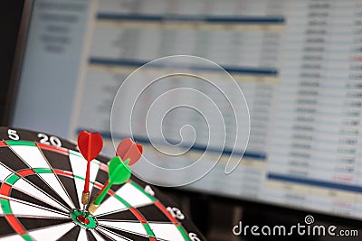 Three Darts hit the target against the background of exchange statistics on the monitor screen Stock Photo