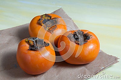 Three delicious caquis on the table Stock Photo