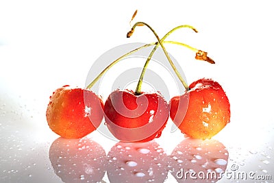 Three delicious ripe sweet cherries with cuttings isolated on a white background with reflection. Side view. Stock Photo