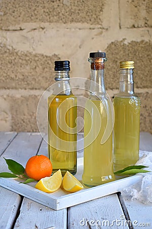 Three delicious yellow alcohol drinks in glass bottles and citrus fruit. Orange-flavored liqueur, Italian Limoncello liquor, tange Stock Photo