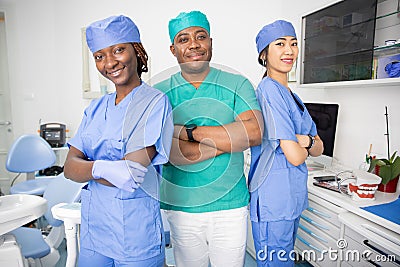 Three dentists pose smiling in a dental office, work in the health sector Stock Photo