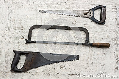 Three different used retro saws in white rustic wooden background Stock Photo