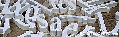 Three-dimensional letters of white letters intended for making advertisements are scattered on the floor Stock Photo