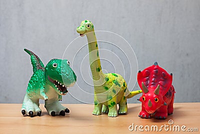 Three dinosaurs toys standing on a wooden floor. Stock Photo