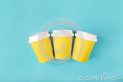 Three disposable paper yellow cups with close plastic lids for takeaway drink coffee, which is then recyclable. Empty mock up flat Stock Photo