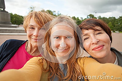 Three diverse happy women friends making selfie photo and having fun outdoors Stock Photo