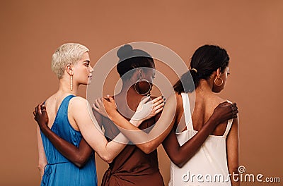 Three diverse women standing against brown background Stock Photo