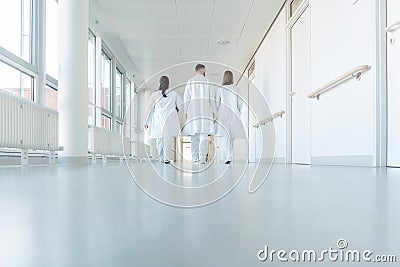 Three doctors walking down a corridor in hospital Stock Photo