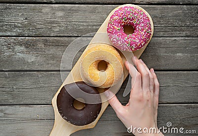 Three donuts on a wooden board background with blank space Stock Photo