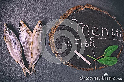 Three dried fish on a black surface Stock Photo