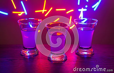 Three drinks at the party. Three shots with cocktails at the bar. Liquor, vodka, fresh. Shining on a colored background. Night clu Stock Photo