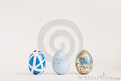 Three Easter golden decorated eggs on blue background. Minimal easter concept. Happy Easter card with copy space for Stock Photo