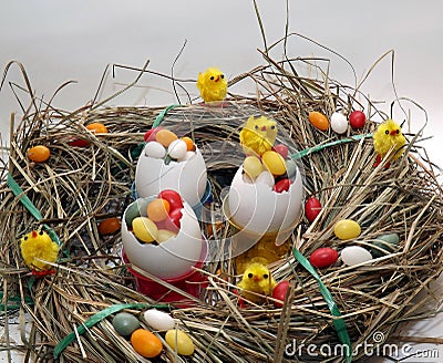 Three egg shells in a cup filled with colorful coated eggs Stock Photo