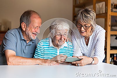 Three elderly persons using smart phone Stock Photo