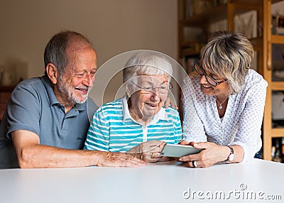 Three elderly persons using smart phone Stock Photo