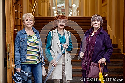 Three elderly women stand at the entrance to the city mall Stock Photo