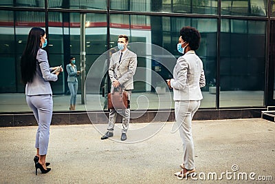 Employers standing in social distance wearing face mask looking at each other and talking Stock Photo