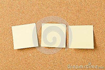 Three empty yellow sticky paper memo notes on cork board Stock Photo