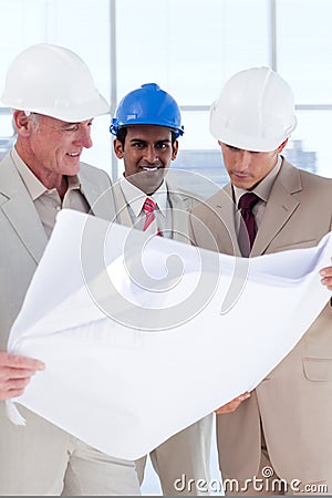 Three engineer co-workers studying plans Stock Photo