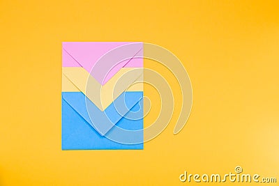 Three envelopes of yellow, blue and pink colors nested in each other lie on a yellow background copy space top view, minimalism co Stock Photo