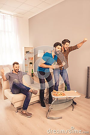 Three excited man celebrating football victory with beer and pizza Stock Photo