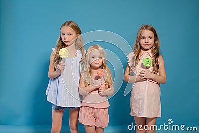 Three fashionable little girls eat candy lollipop Stock Photo