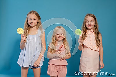 Three fashionable little girls eat candy lollipop Stock Photo