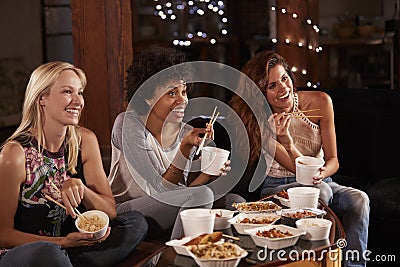 Three female friends eating a Chinese take-away watching TV Stock Photo