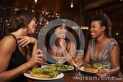 Three female friends eating dinner together at a restaurant Stock Photo